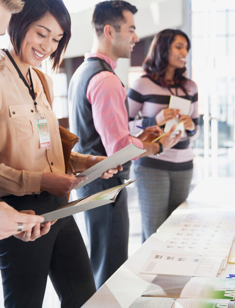 People standing in front of a table signing into a conference