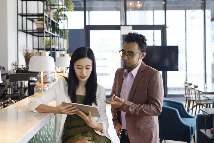 People sitting in a coworking space looking at a tablet