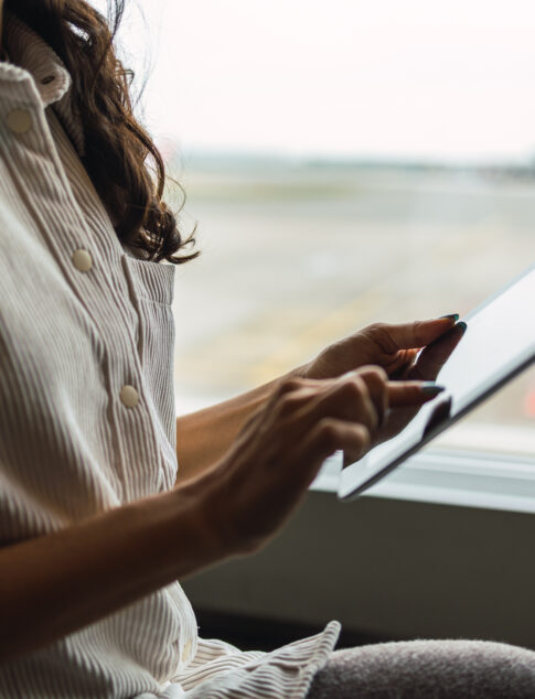 Woman scrolling through her tablet at an airport lounge