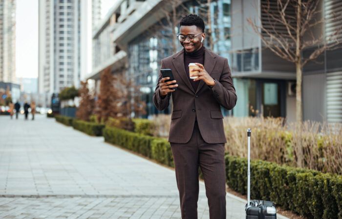 Man Smiling at Phone While Holding Coffee