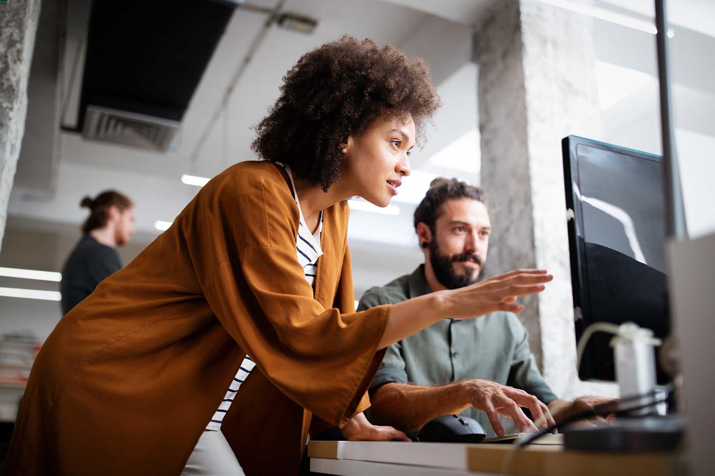 Business team collaborating at a computer in an office while working on a project