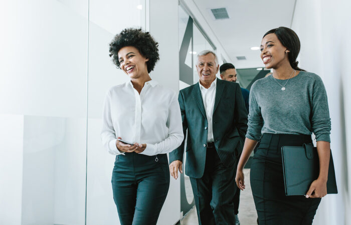 Corporate Professionals Discussing While Walking Through Corridor